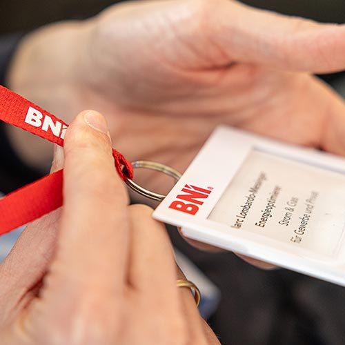 Hands holding BNI conference name badge and lanyard
